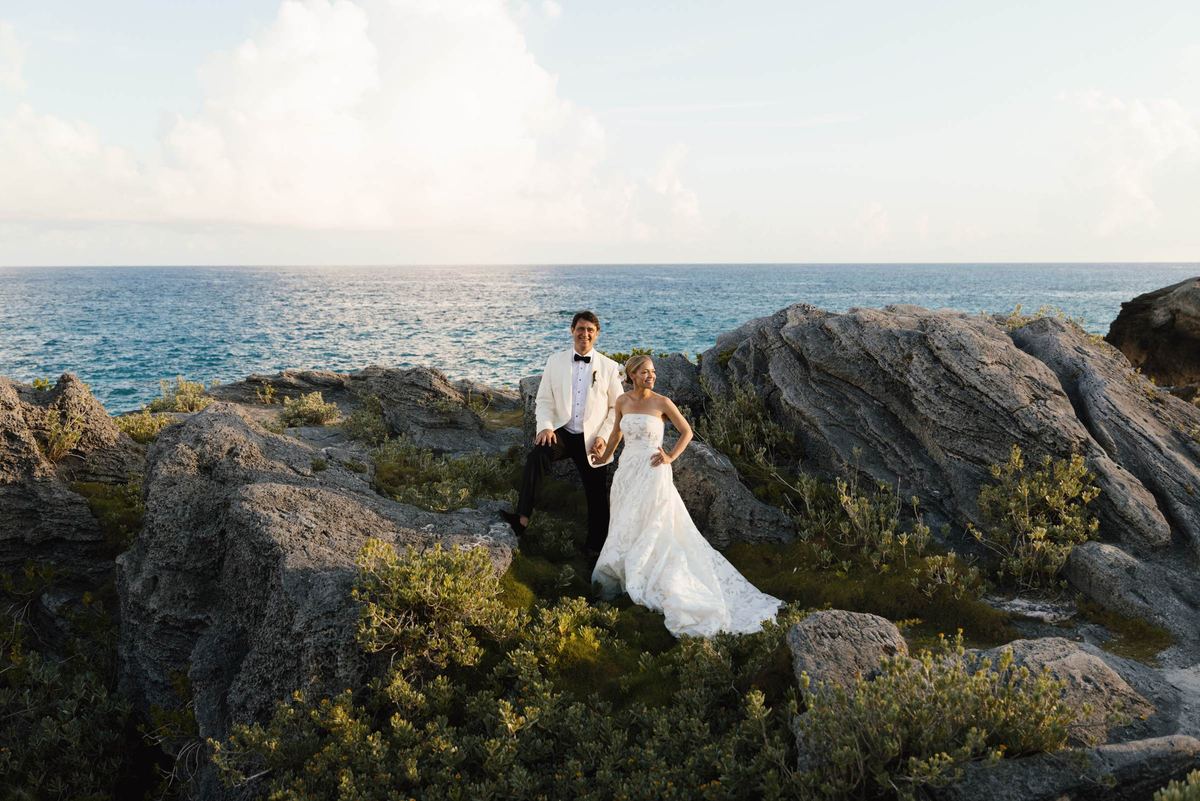 Bride and groom on the rocks above the Bermuda ocean at golden hour