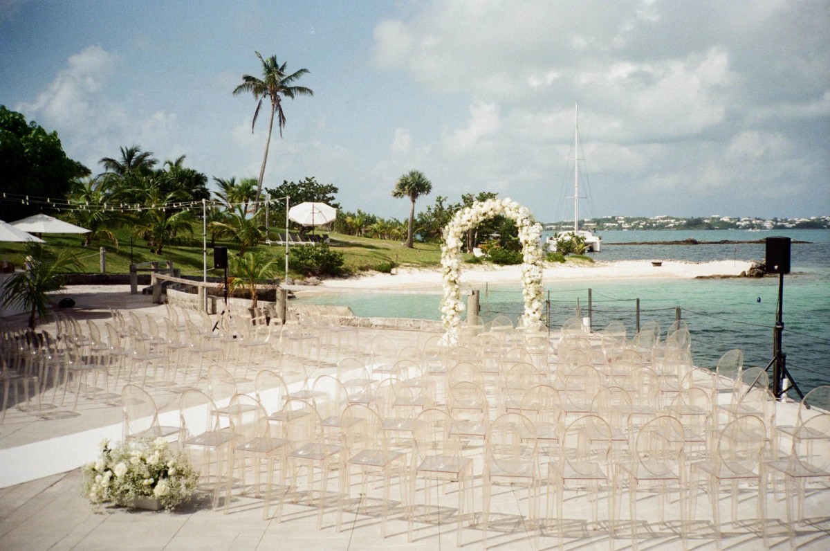 The ceremony set up on the waterfront terrace with palms and the bay beyond on Hawkins Island, Bermuda, on film