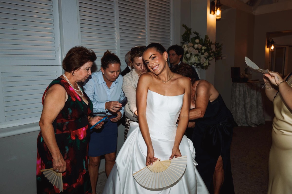 Bride dancing with a paper fan surrounded by family at Rosewood Bermuda
