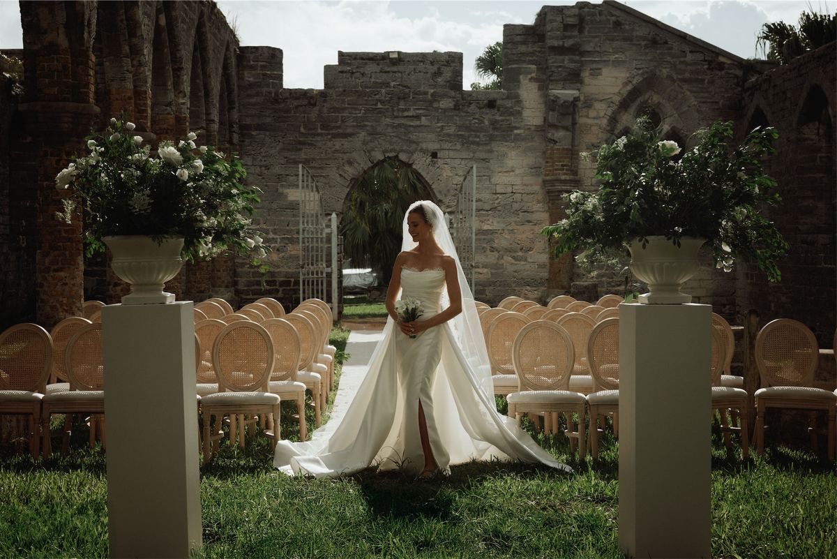 Bride standing alone in the ruins between flower urns before the ceremony