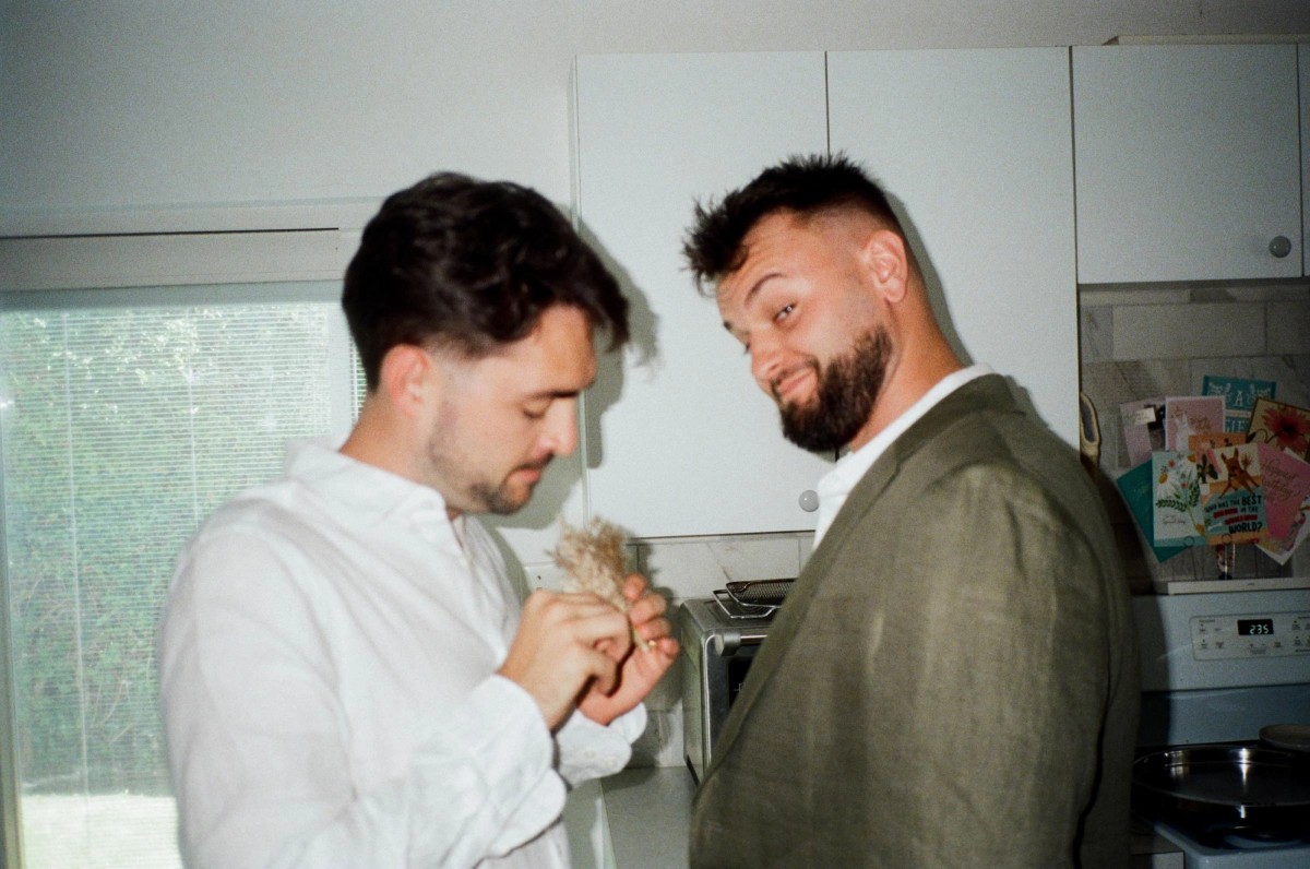Groom and his best man fixing a boutonniere in the kitchen, shot on film
