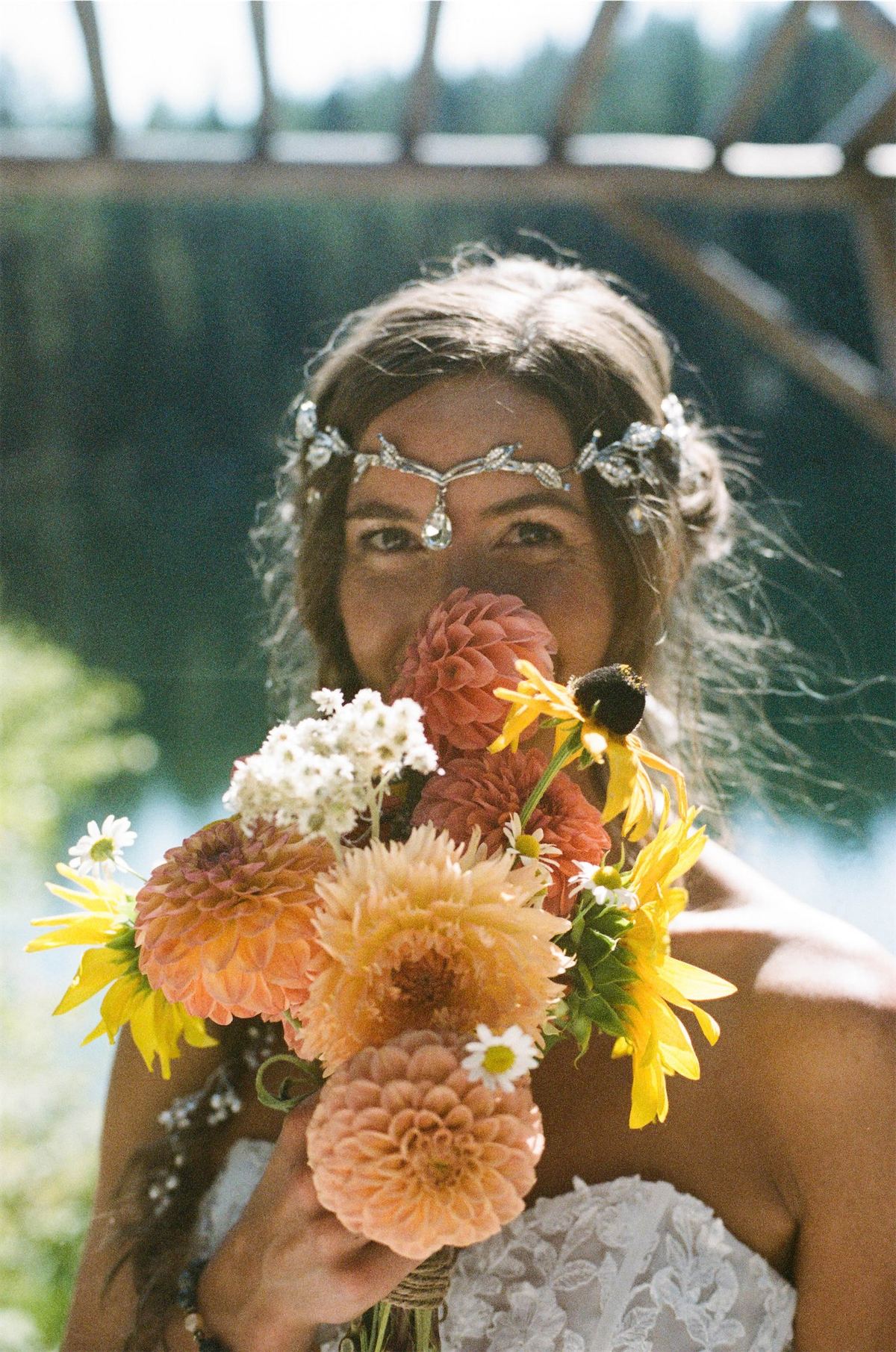 Bride lifting a bouquet of dahlias and sunflowers up to her face