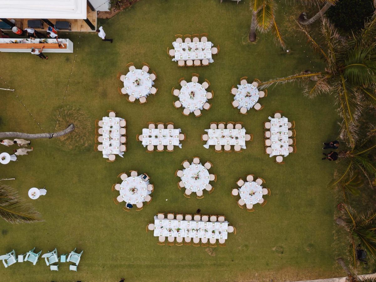Aerial view of round reception tables set on the lawn above a Bermuda beach