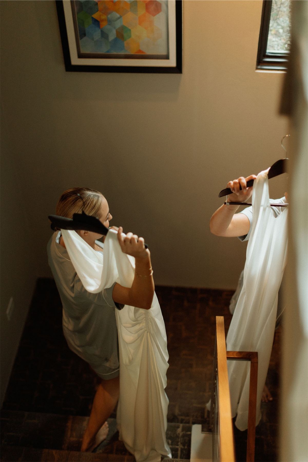 Bride being helped into her gown on the stairs while getting ready
