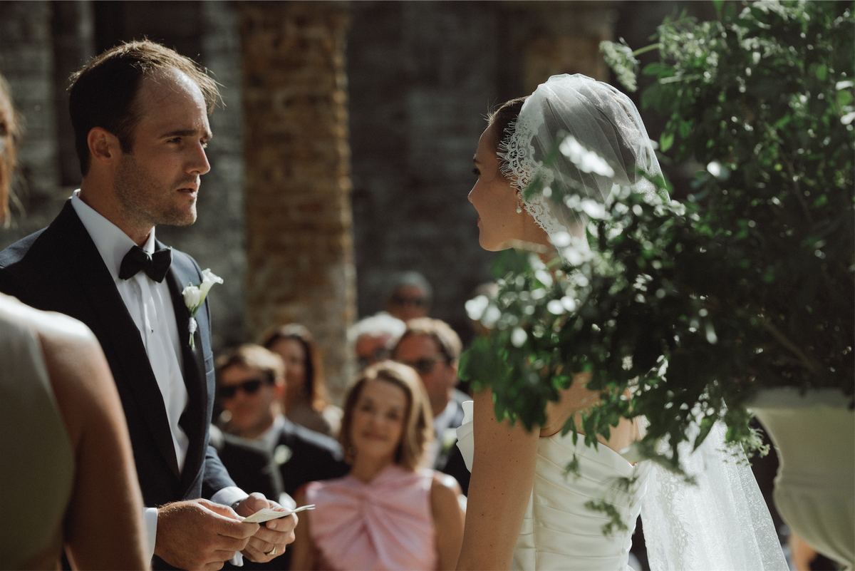 Groom smiling at his bride mid-ceremony as seated guests look on