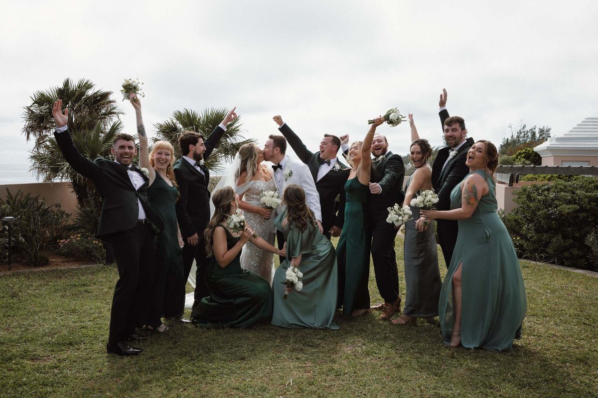 Bridal party celebrating with arms raised around couple at Bermuda wedding