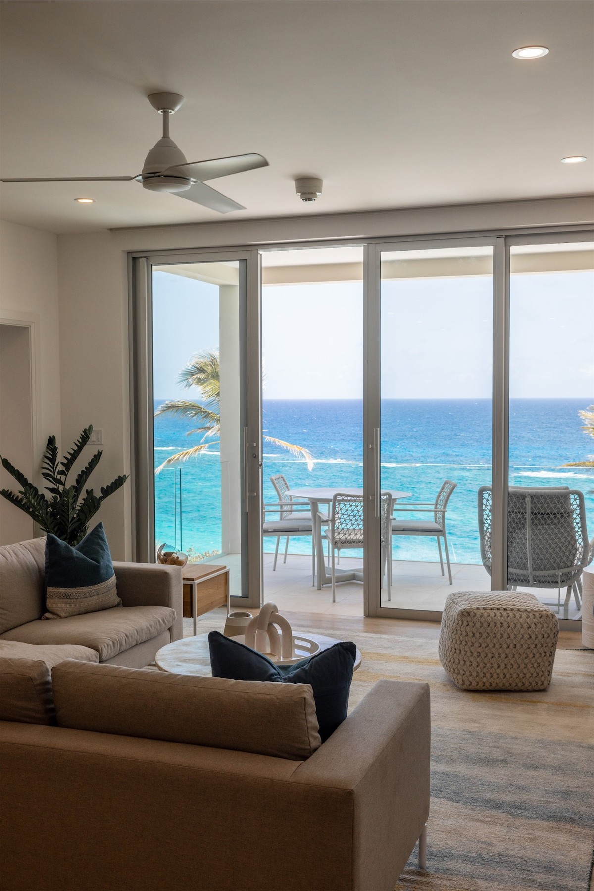 Open-plan resort living room framing the ocean through full-height glass doors