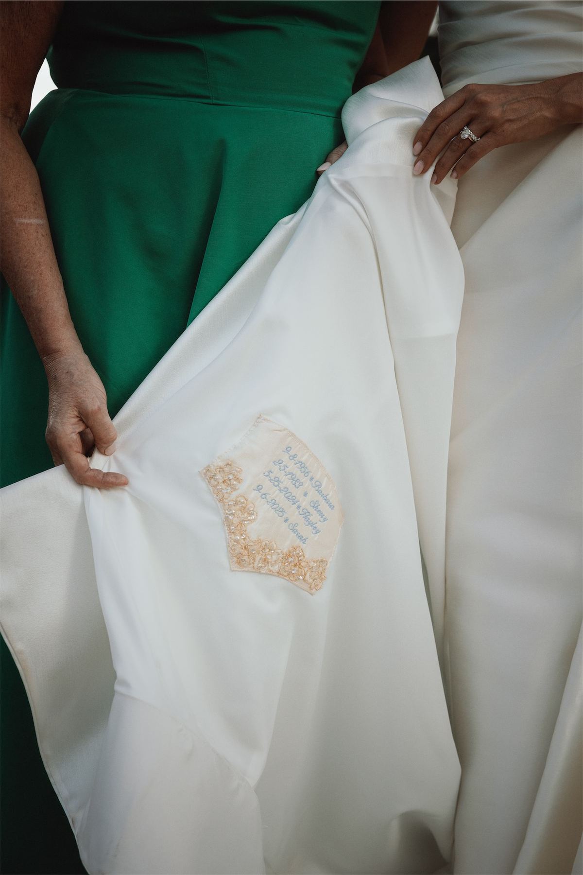 Bridesmaid in green revealing an embroidered message stitched inside the bride's gown
