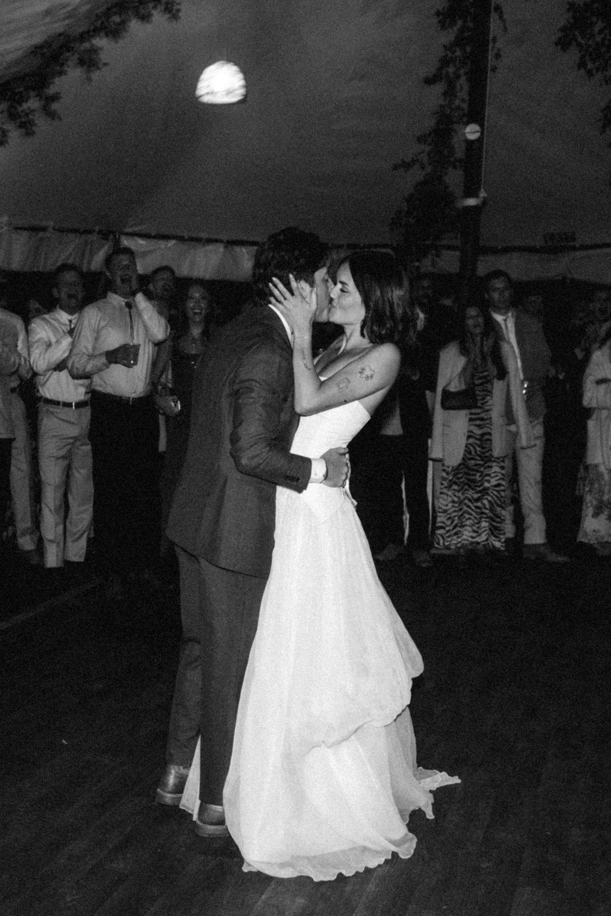 Devin and Owen kiss during their first dance under the tent at a mountain ranch among the aspens, black and white