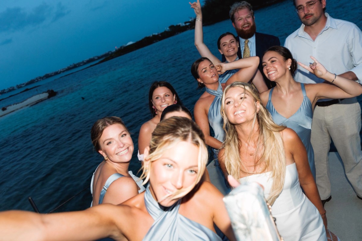 Paige and her bridesmaids pull a flash lit selfie by the water at blue hour on Hawkins Island, Bermuda