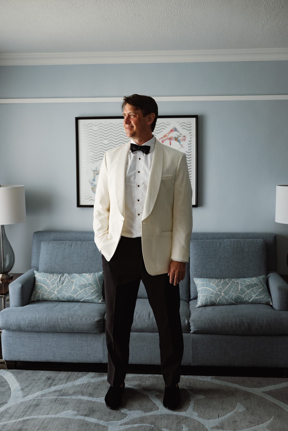 Groom in a white dinner jacket waiting in his room before the ceremony