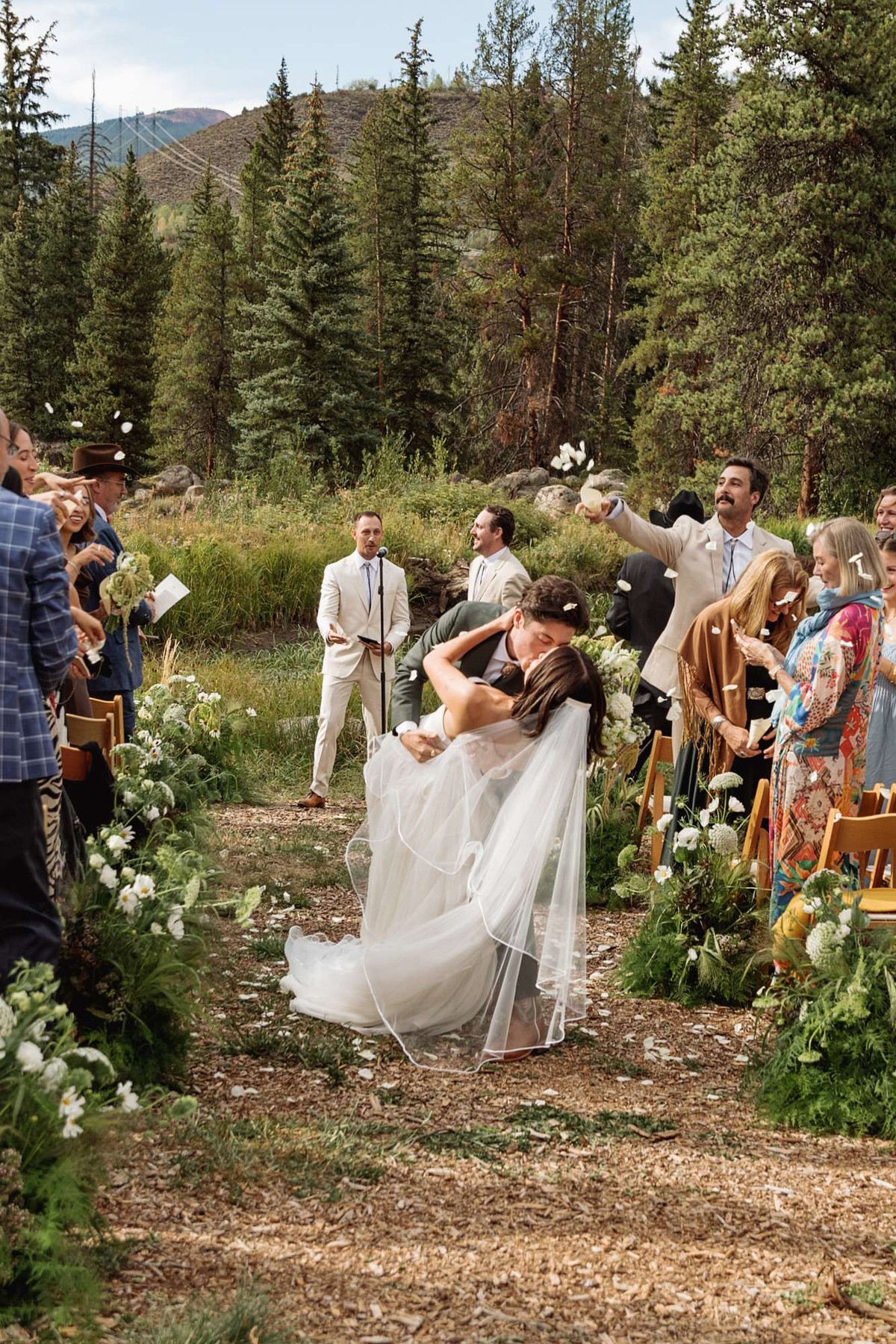 Owen dips Devin in the aisle as guests cheer at a mountain ranch among the aspens