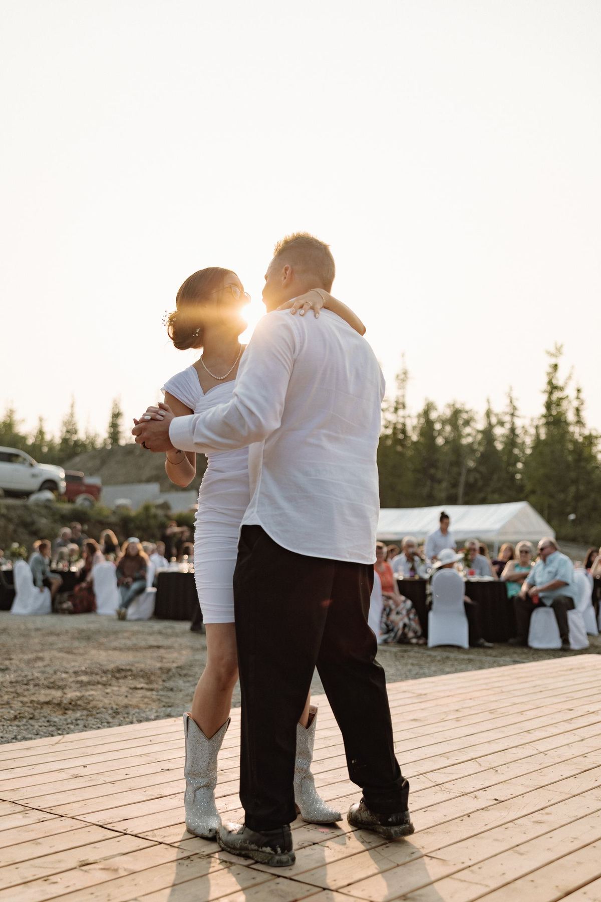 Bride and groom dancing at sunset on the wooden deck above the valley