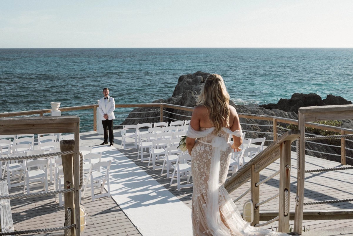 Bride approaching ceremony aisle with ocean view at Bermuda destination wedding