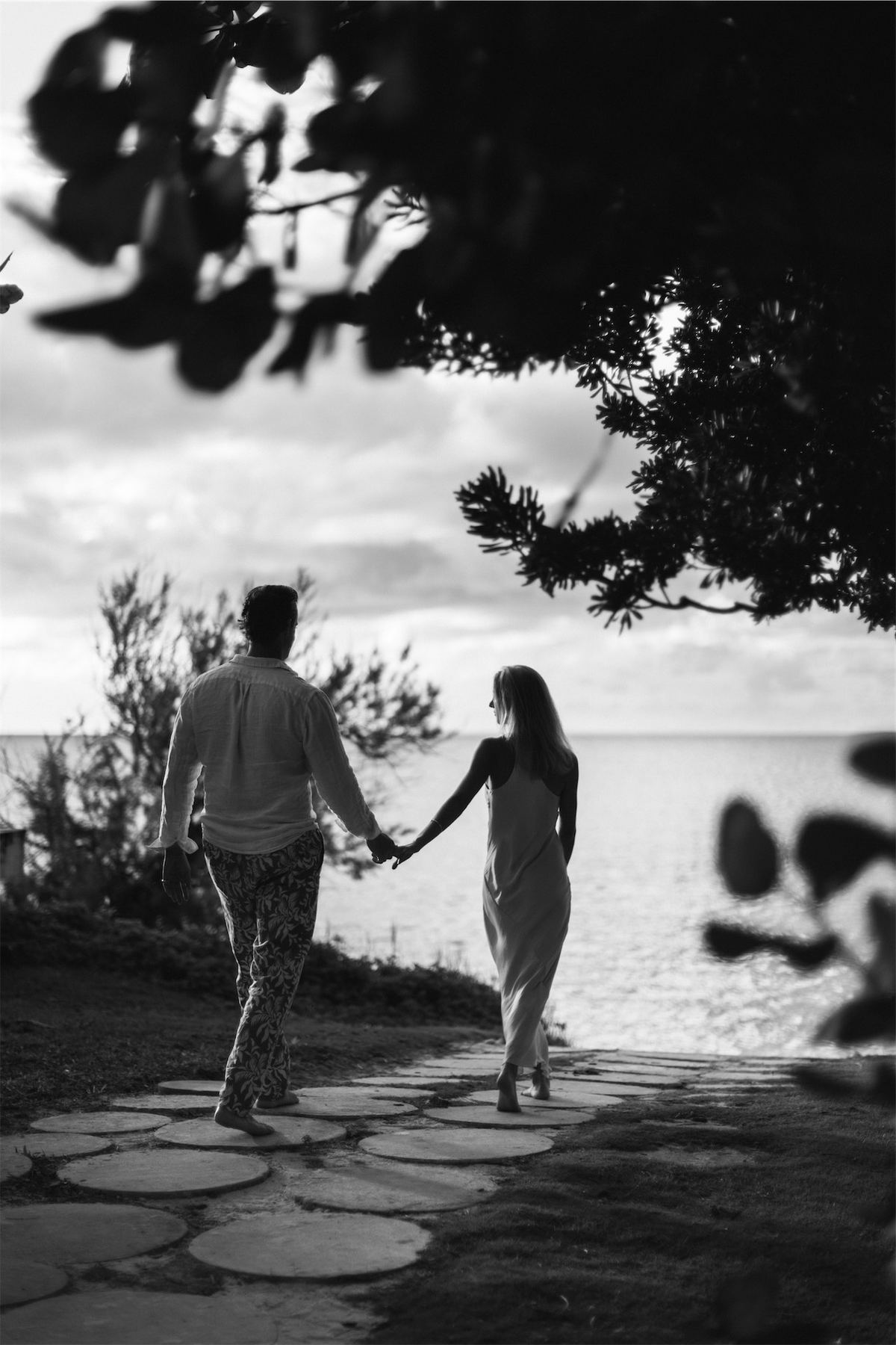 Black and white of the couple walking hand in hand along a coastal path