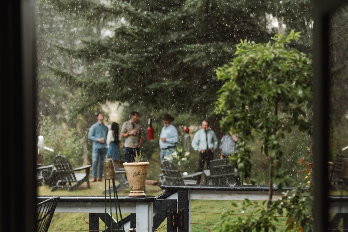 Guests in the garden seen through a rain flecked window at a mountain ranch among the aspens