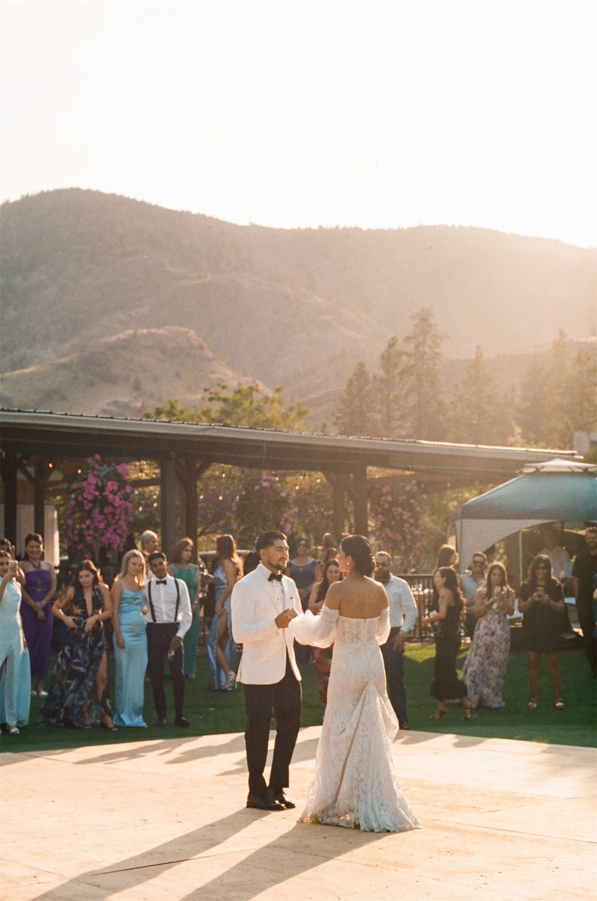 First dance on the terrace at sunset with guests circled around and mountains behind