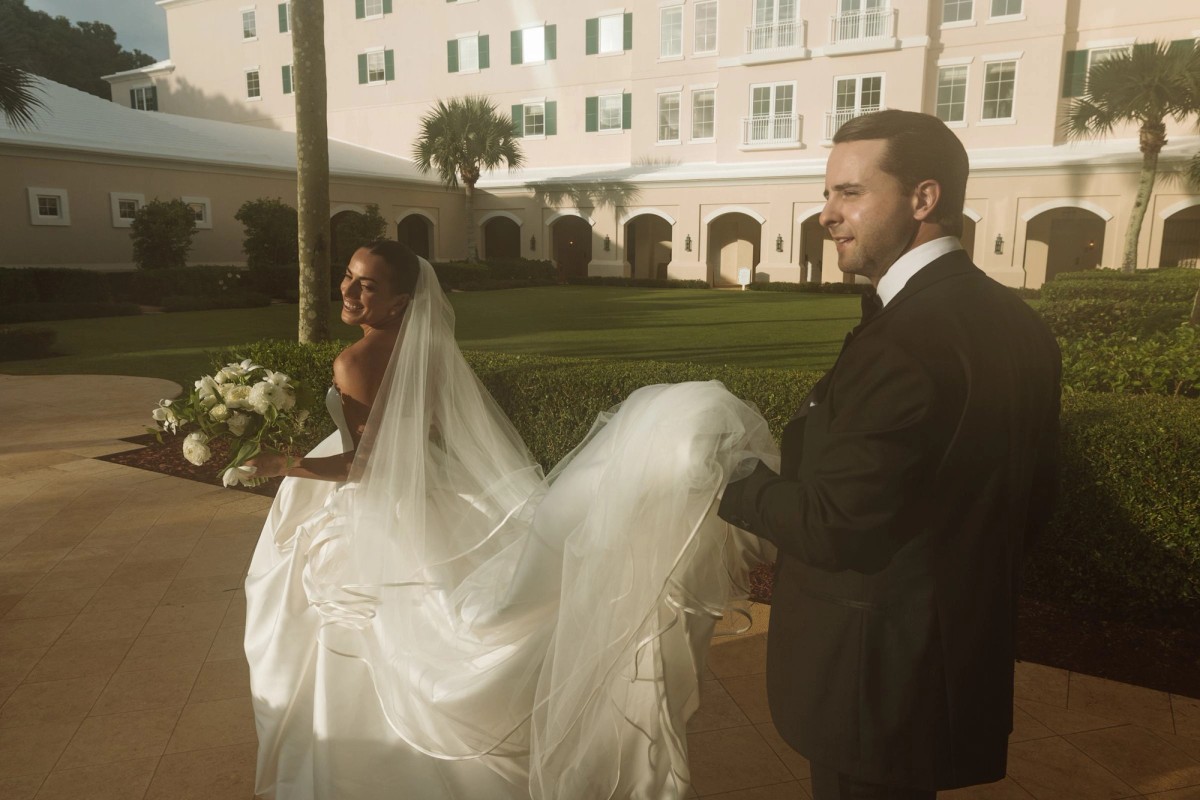 Juliana looks back over her veil as Casey gathers her train in golden light at Rosewood Bermuda