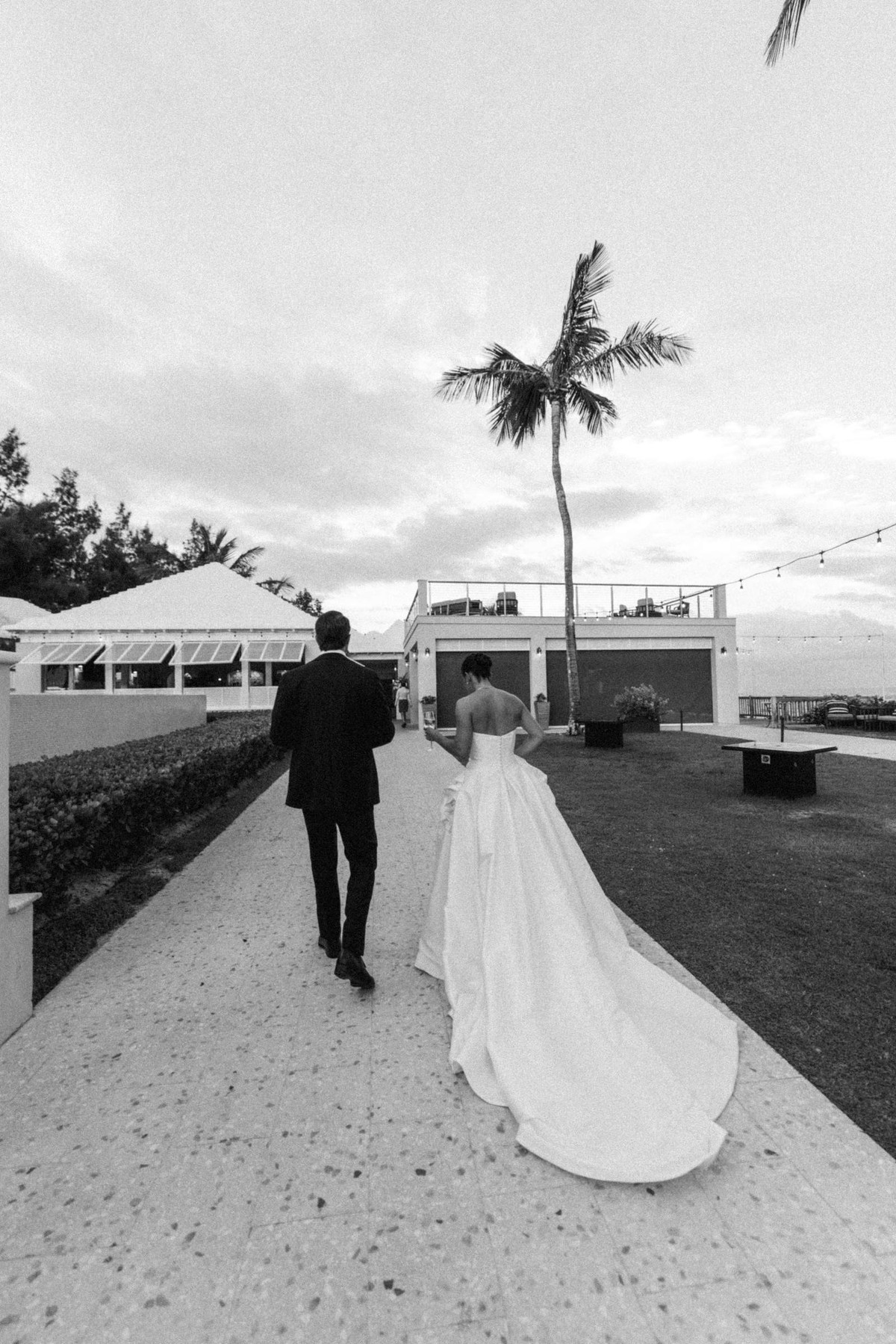 Couple walking toward the sea past a lone palm at Rosewood Bermuda, black and white