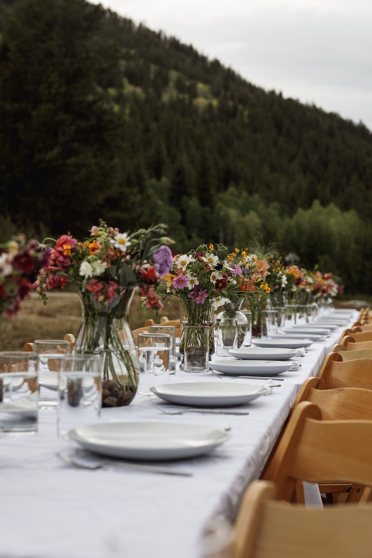 Wildflower vases line the long welcome party table at a mountain ranch among the aspens