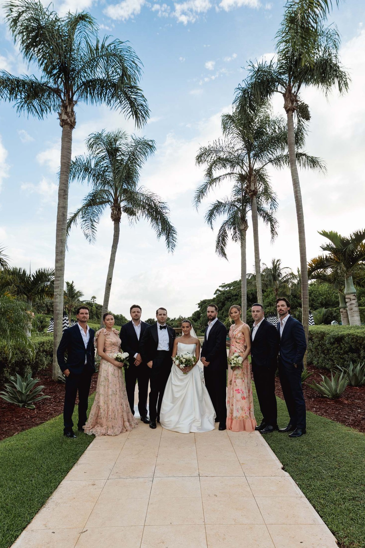 Wedding party lined up under tall palms on the garden path at Rosewood Bermuda
