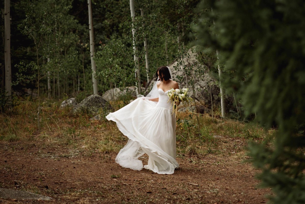 Devin spins her skirt holding her bouquet on the forest trail at a mountain ranch among the aspens