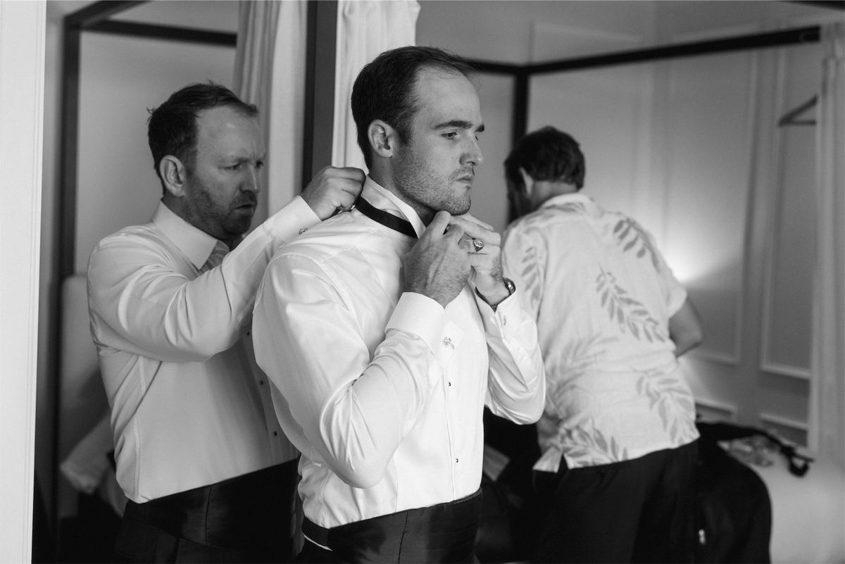 Black and white of the groomsmen helping each other with bow ties