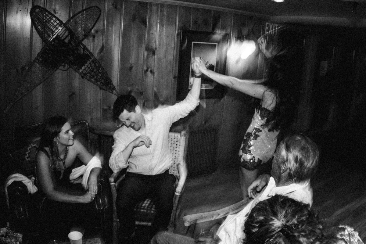 Owen dances with friends at the after party in the lodge at a mountain ranch among the aspens, black and white