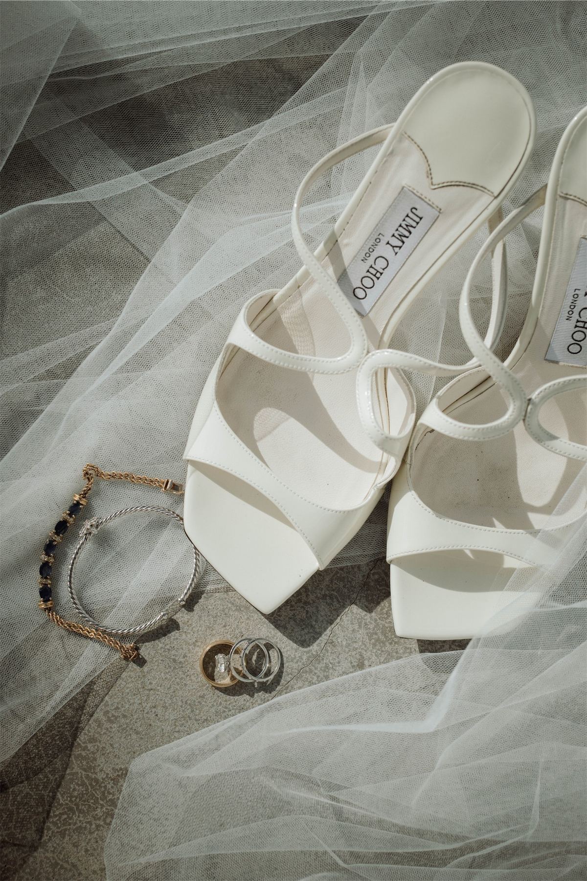 Bridal heels, bracelet and wedding rings laid out on the veil