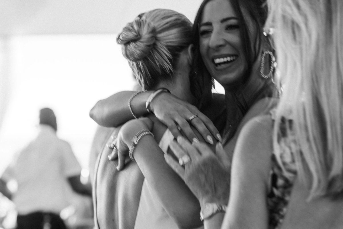 Black and white candid of two guests hugging and laughing at a Bermuda wedding