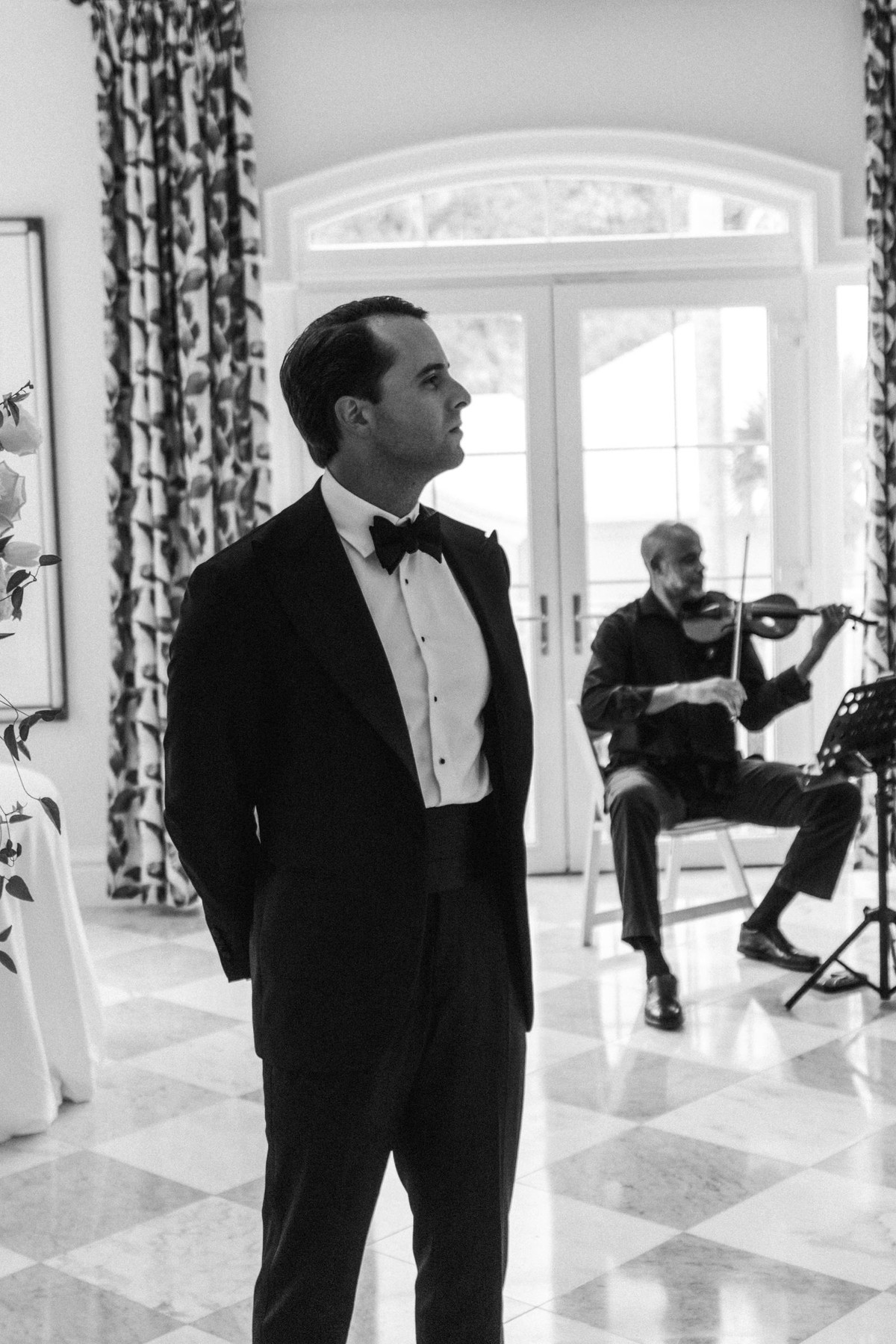 Groom watching the aisle as the violinist plays at Rosewood Bermuda, black and white