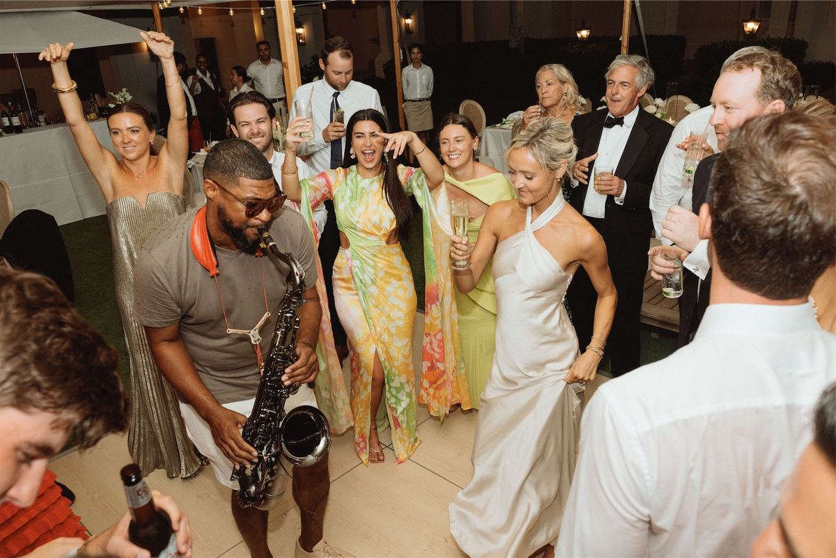 Guests dancing around a saxophone player at the reception