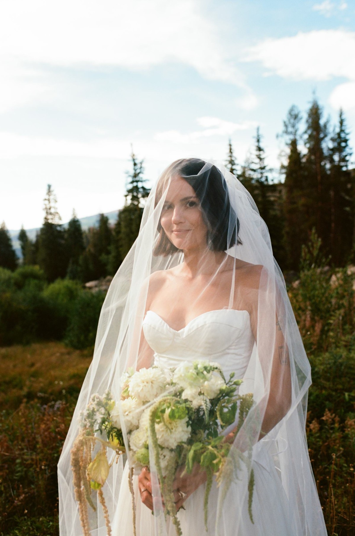 Devin under her veil holding her bouquet, shot on film at a mountain ranch among the aspens