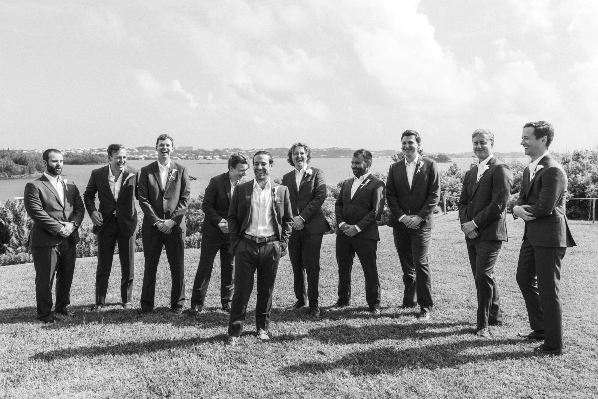 Groomsmen line up on the lawn in dark suits on Hawkins Island, Bermuda, black and white