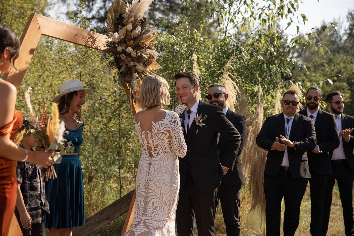 Bride and groom laughing with guests beside the pampas ceremony arch