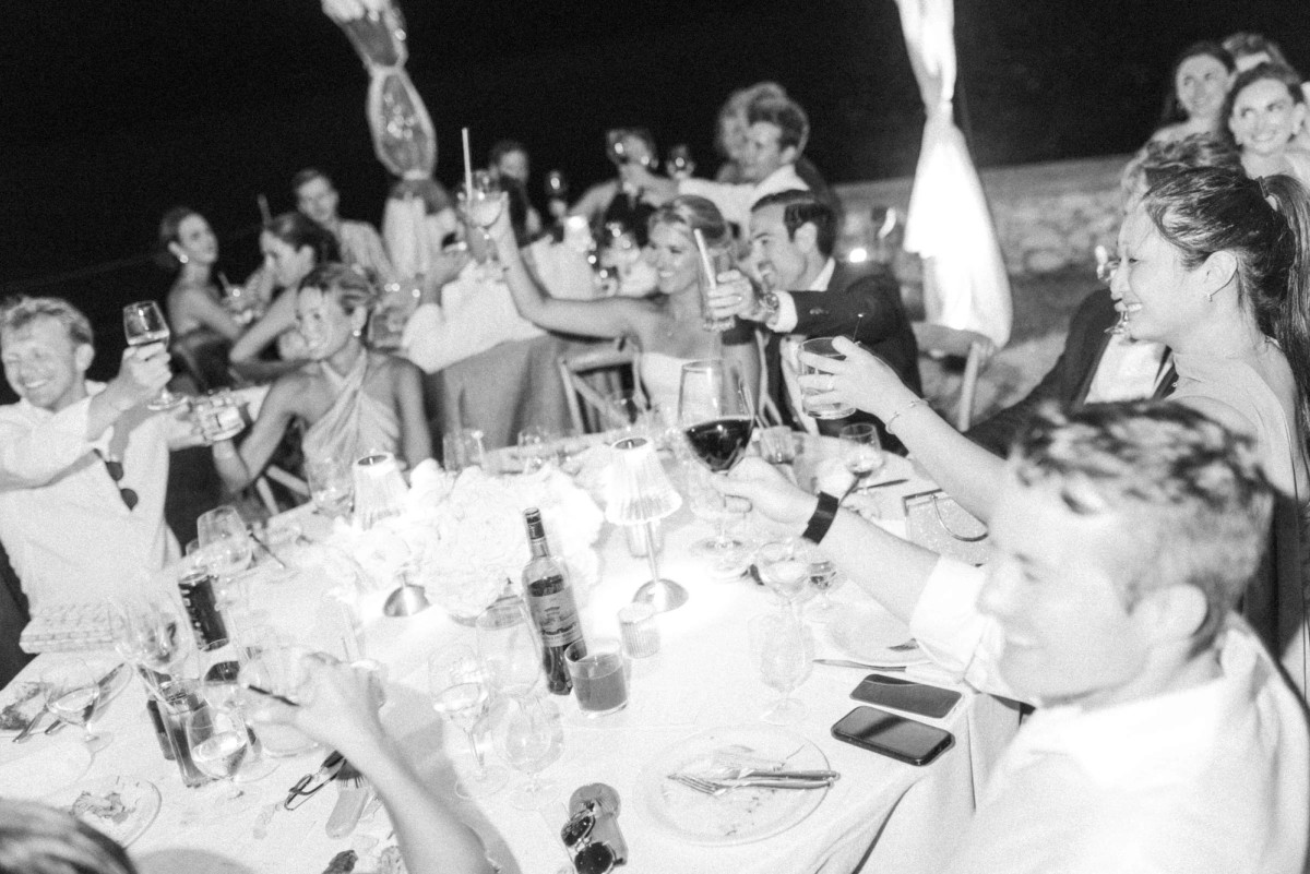 Guests raise glasses around a candlelit table on Hawkins Island, Bermuda, black and white