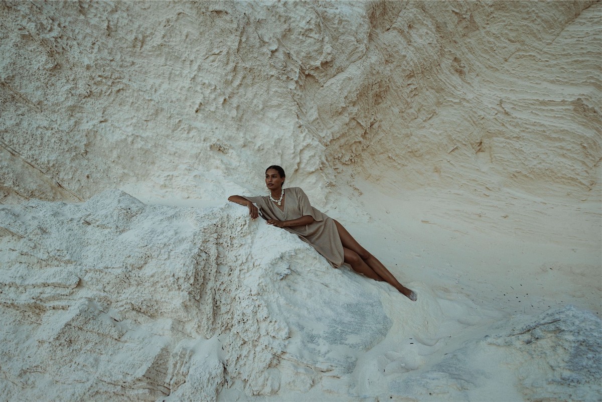Model reclining across a white limestone outcrop in a matching linen set