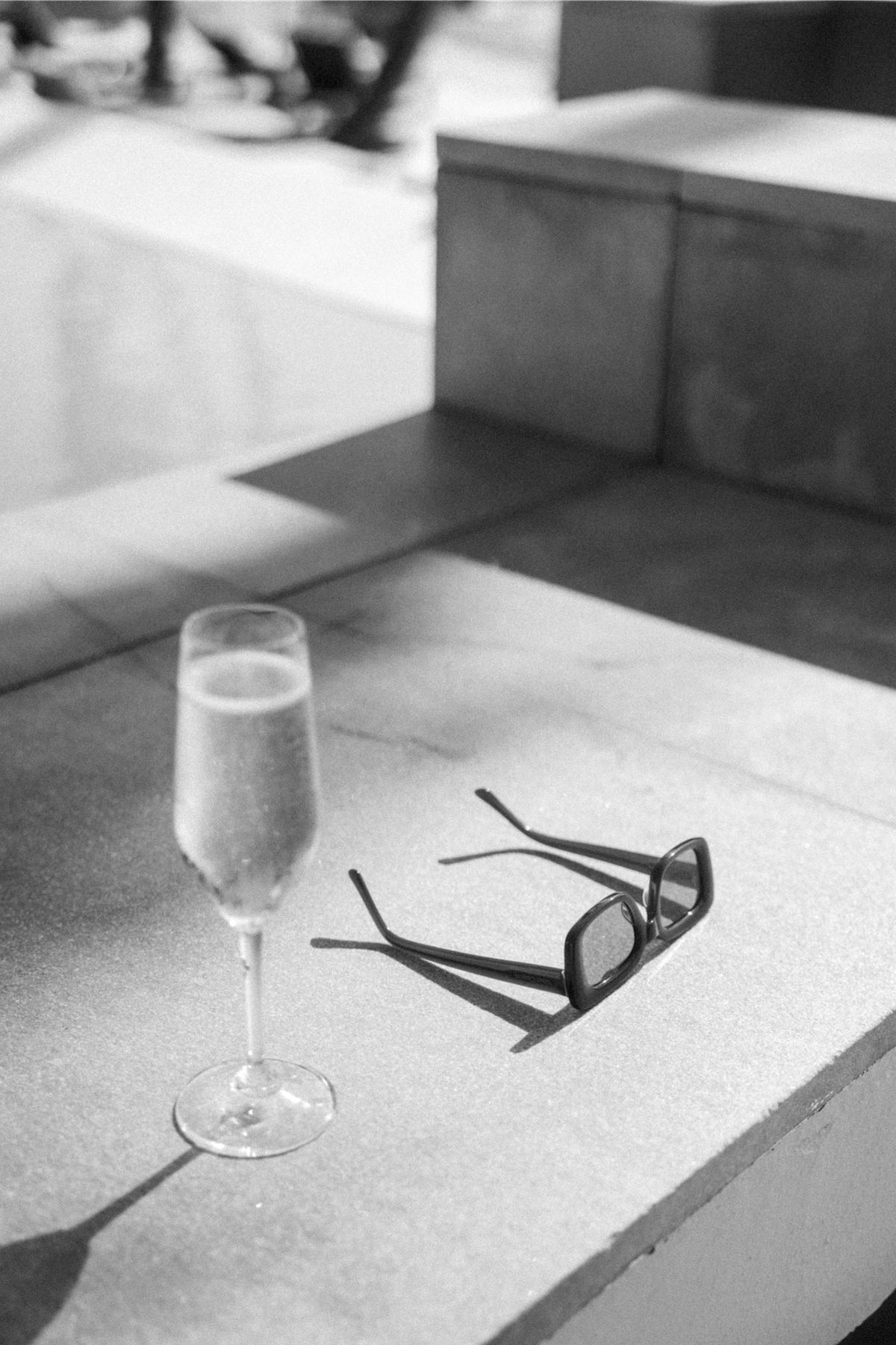 Black and white still life of a champagne flute and sunglasses on stone steps
