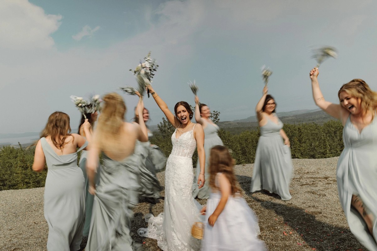 Bridal party cheering with bouquets flying at a mountaintop wedding