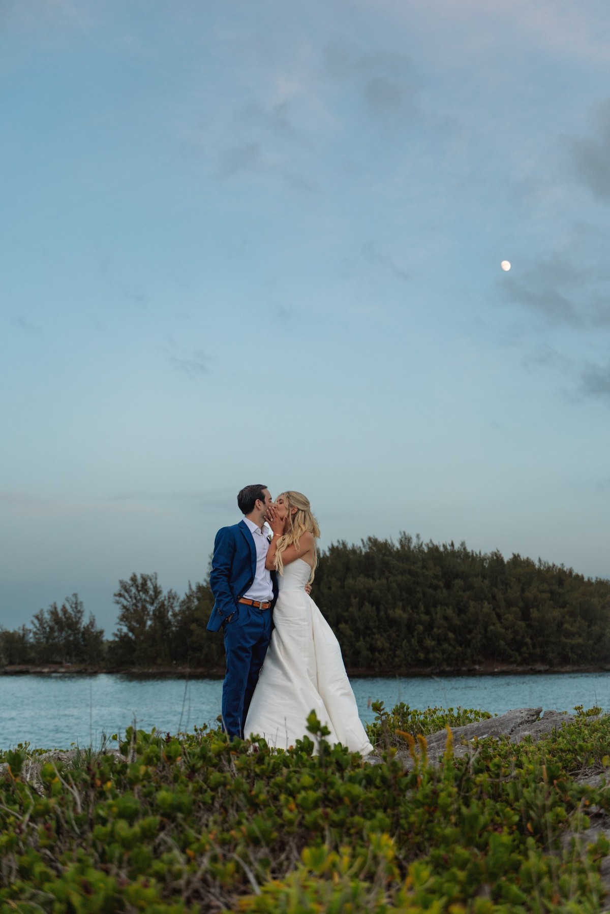Paige and Cam kiss on the headland as the light fades on Hawkins Island, Bermuda