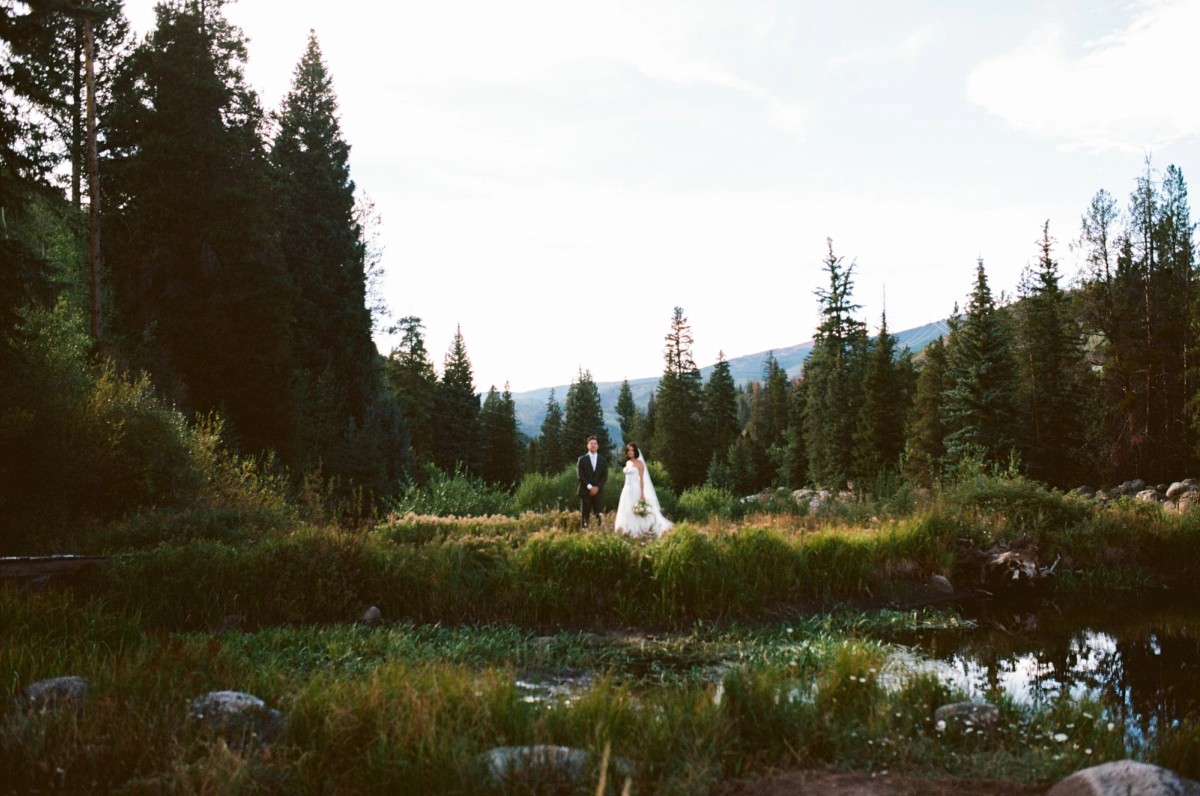 Devin and Owen stand beside the pond at dusk, shot on film at a mountain ranch among the aspens
