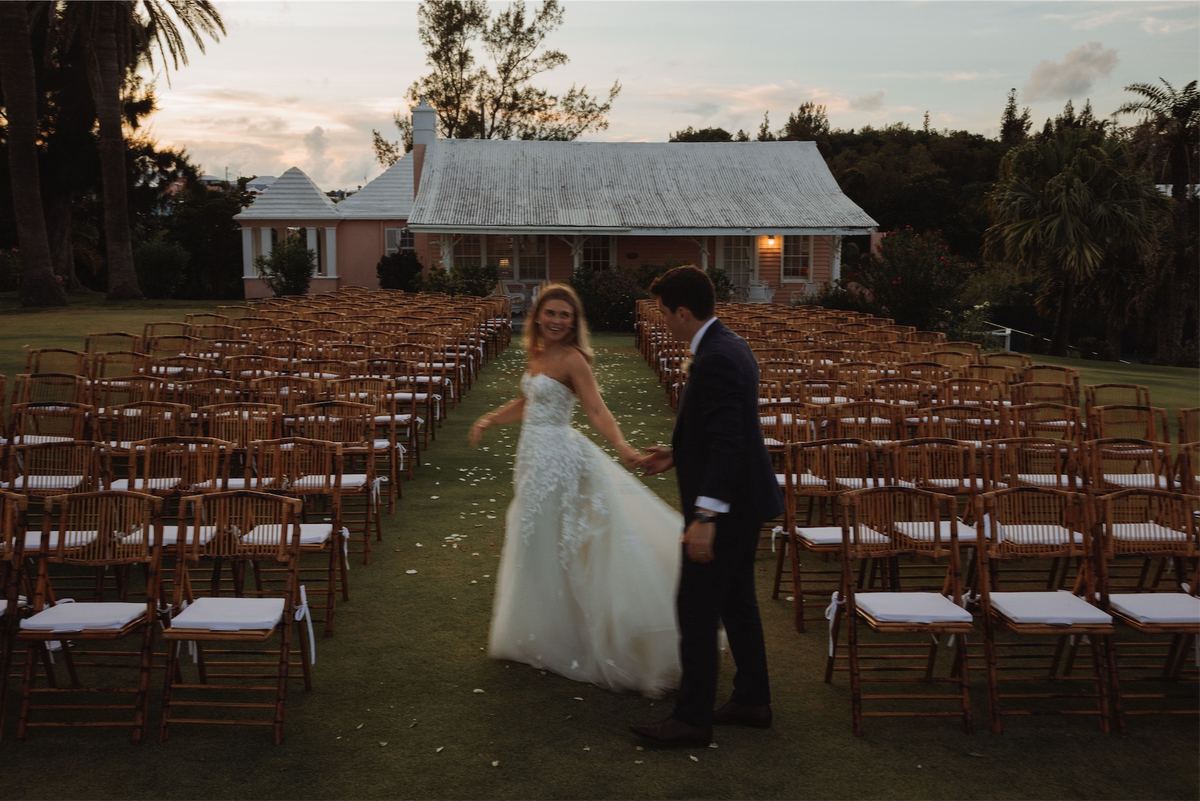 Bride and groom alone in the aisle at sunset in front of a Bermuda cottage