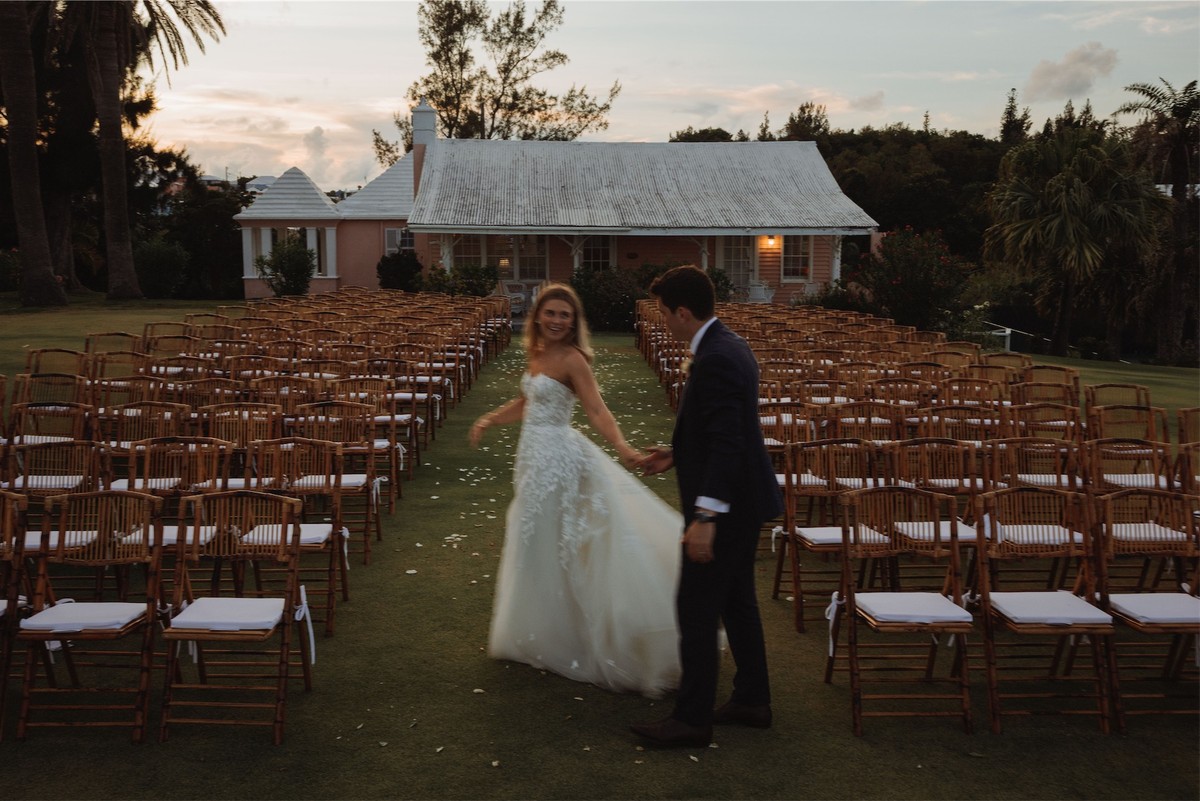Bride and groom alone in the aisle at sunset in front of a Bermuda cottage