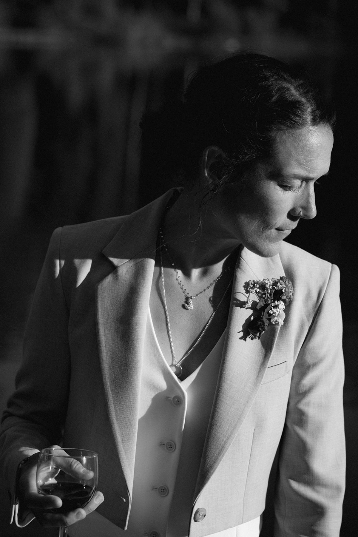 Black and white portrait of a bride in a tuxedo jacket with a boutonniere