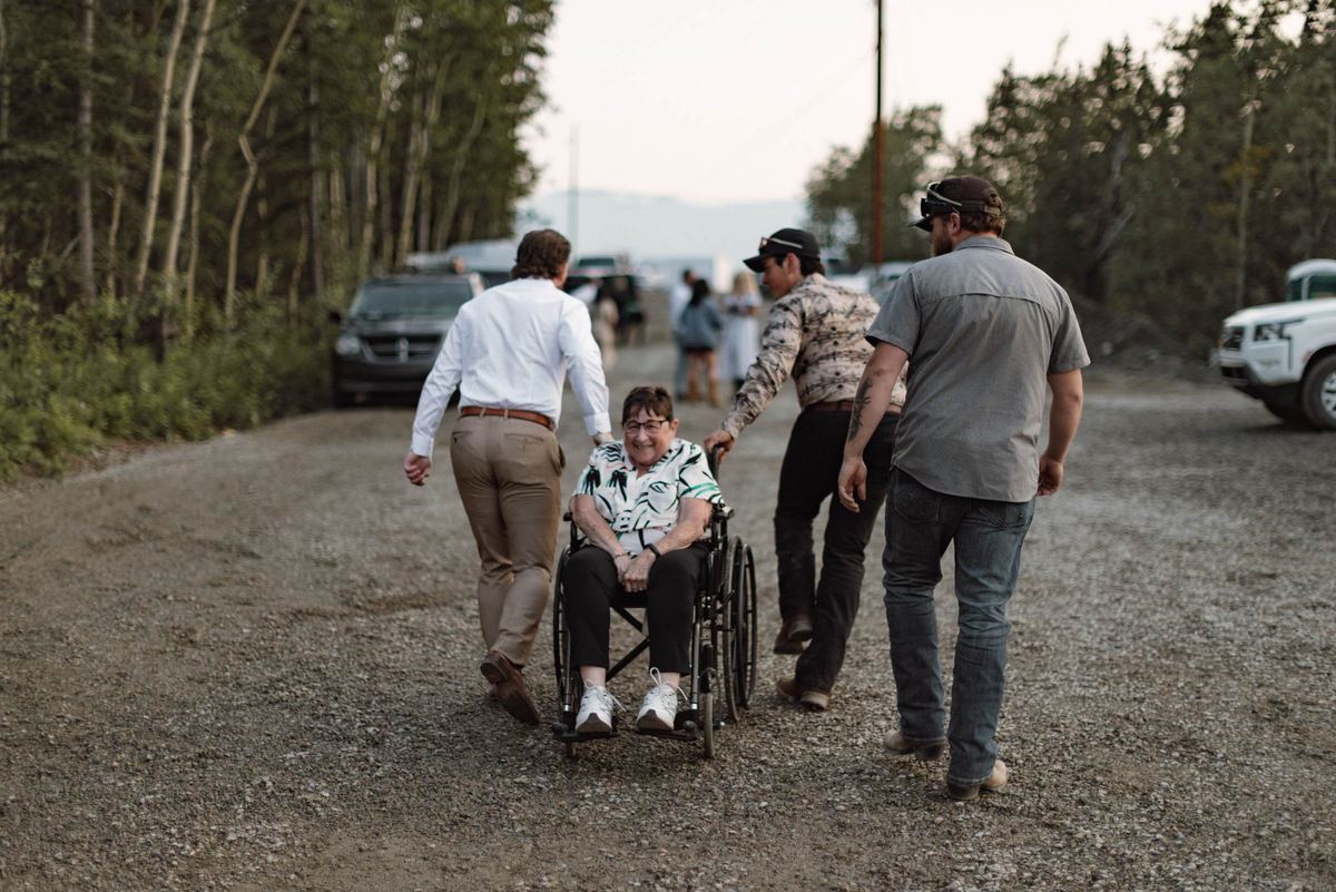 Guests pushing a friend in a wheelchair up the road to the reception