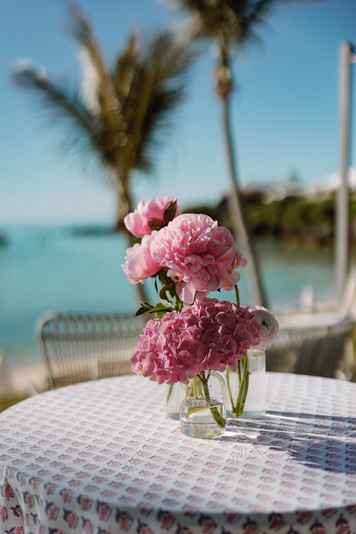 Pink peonies on a linen table with the Bermuda ocean soft behind them