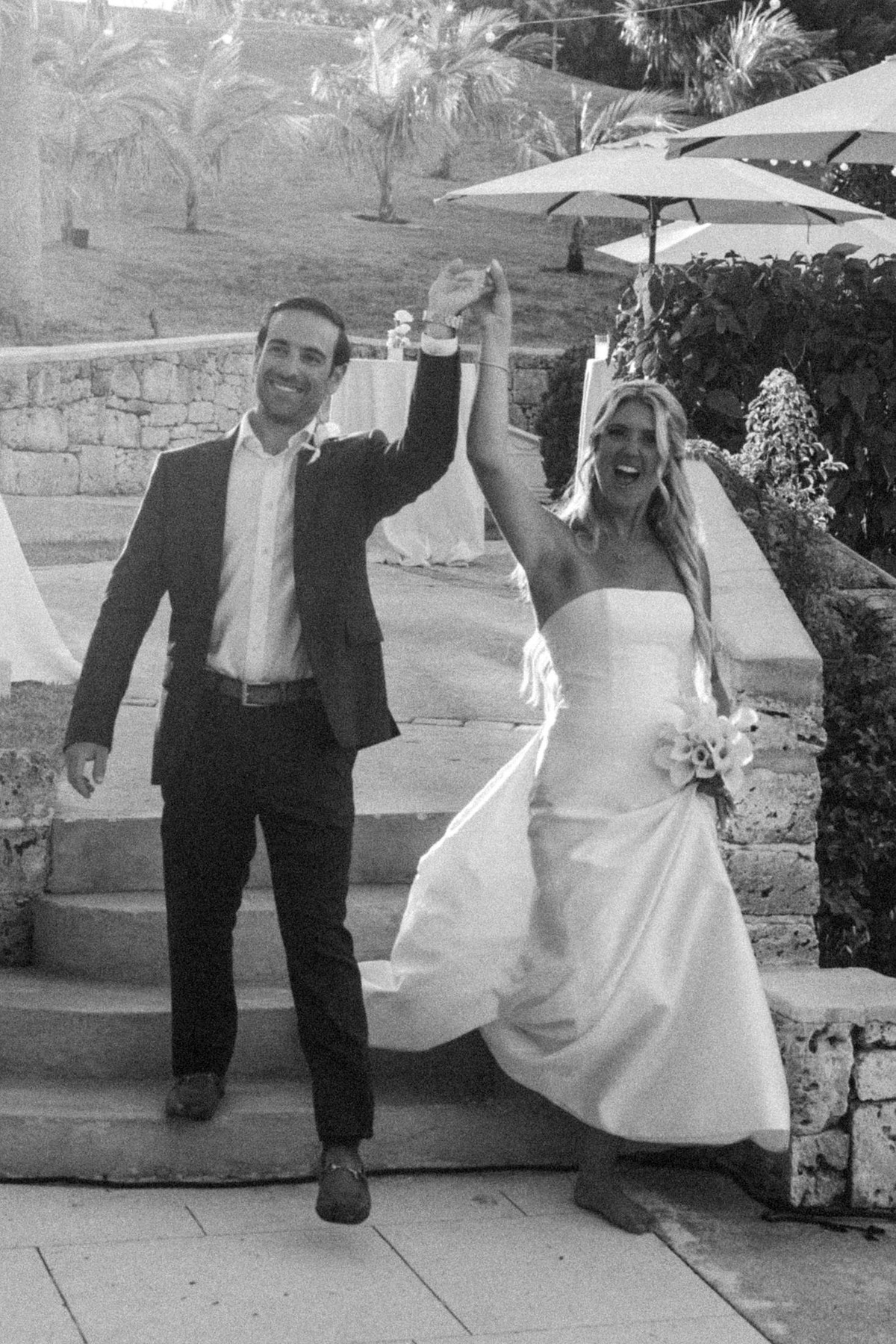 Paige and Cam dance down the steps into the reception on Hawkins Island, Bermuda, black and white