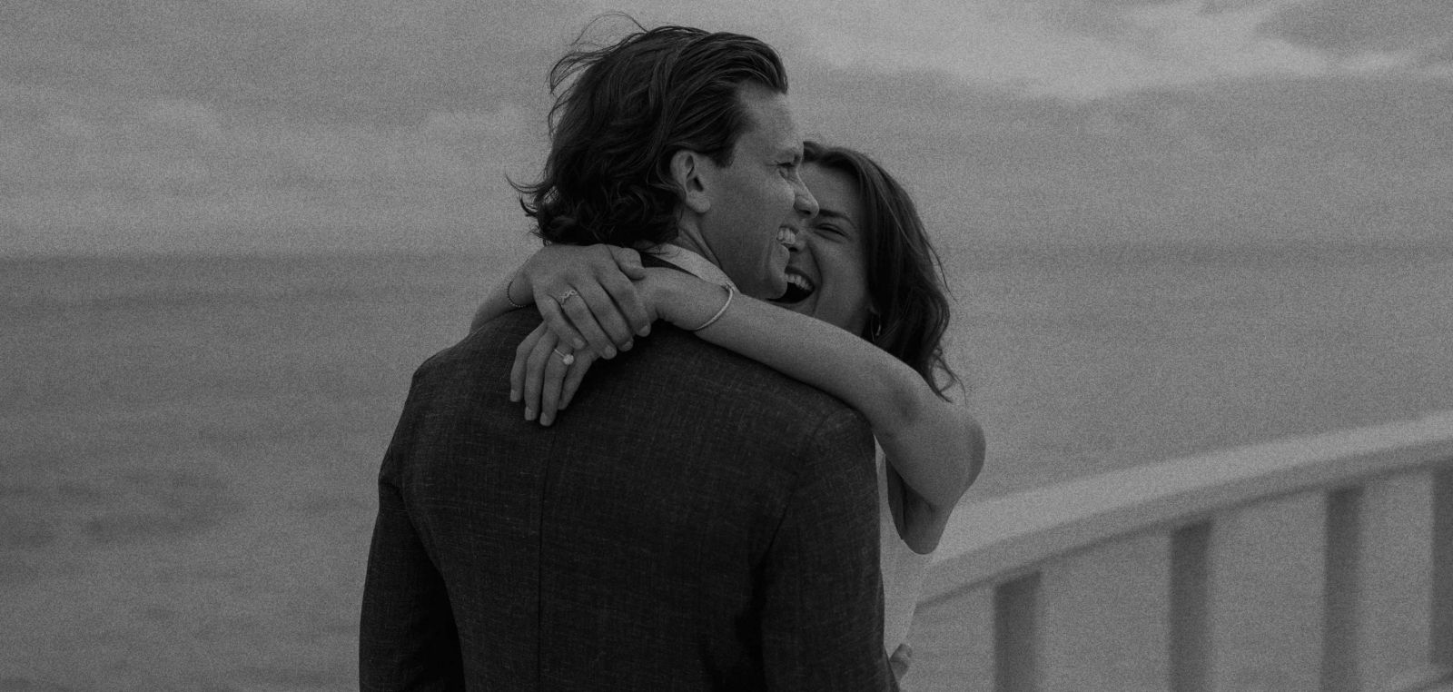Black and white photograph of a couple embracing beside the ocean