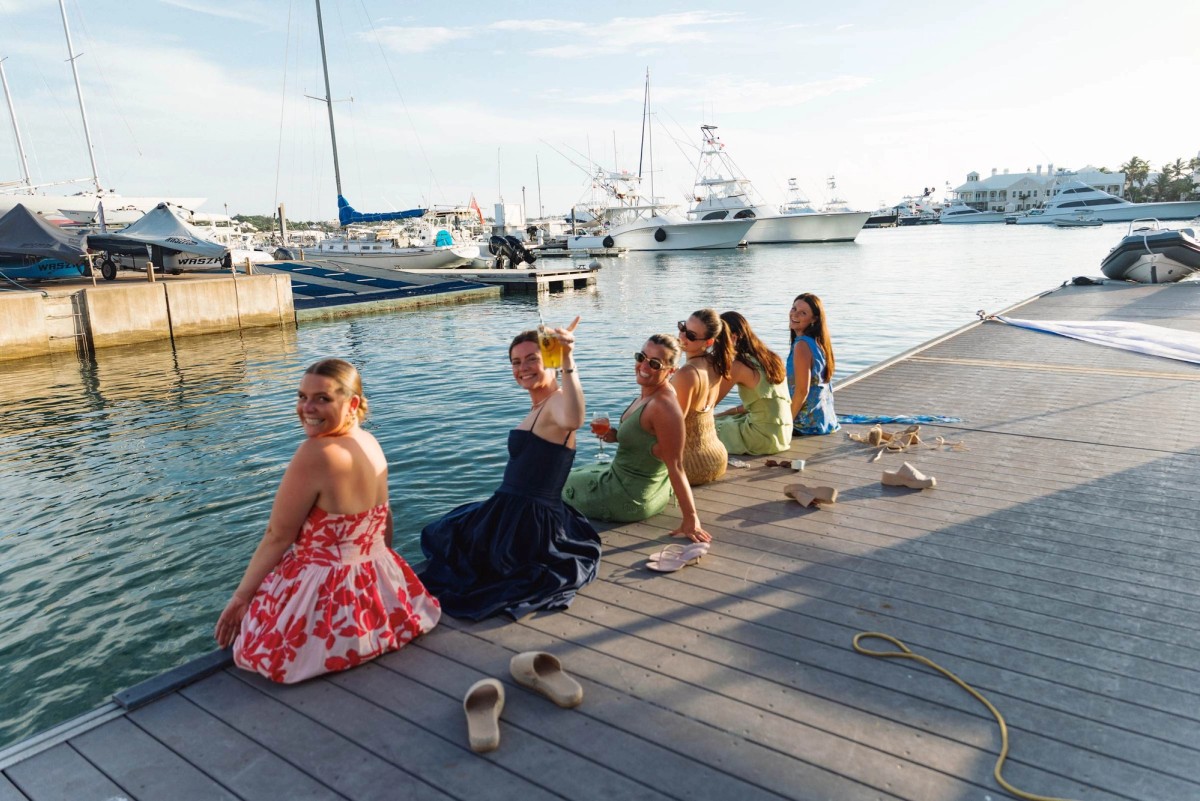 Guests sit along the marina dock at the welcome party, drinks raised in Bermuda