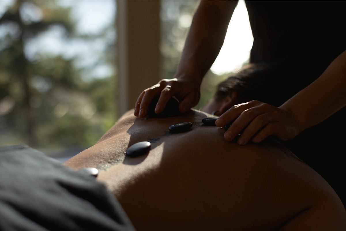 Hot stone massage underway, the therapist's hands working across a client's back